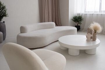 Large living-room with white comfortable sofa and armchair and round table with group of handmade...