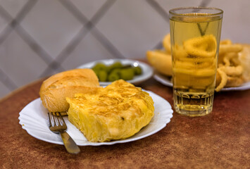 Spanish tortilla and fried calamari with green olives and cider in Madrid, Spain