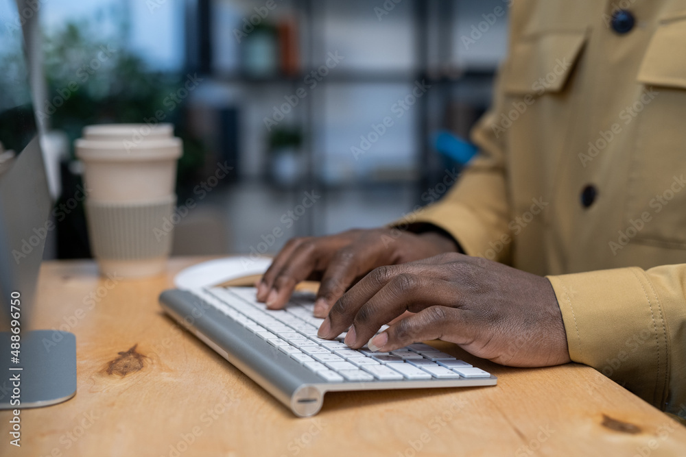 Poster hands of young african-american businessman pressing keys of computer keyboard while working in the 