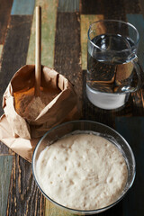 Wheat flour in a craft package. Freeze movement, spoon dark background, sprinkle flour. Front view.