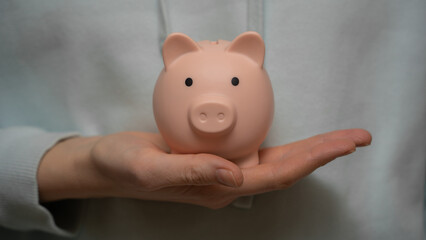 Women's hands hold a piggy bank close-up. Saving and accumulating money, financial security, budget planning and investment.