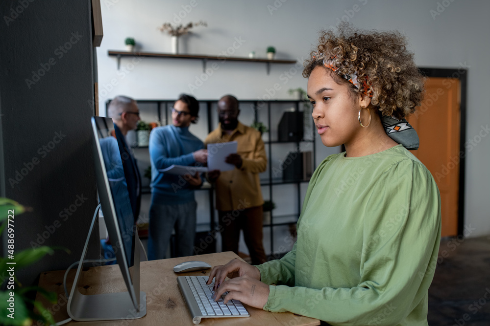 Poster young pretty biracial businesswoman looking at computer screen while preparing for presentation or a