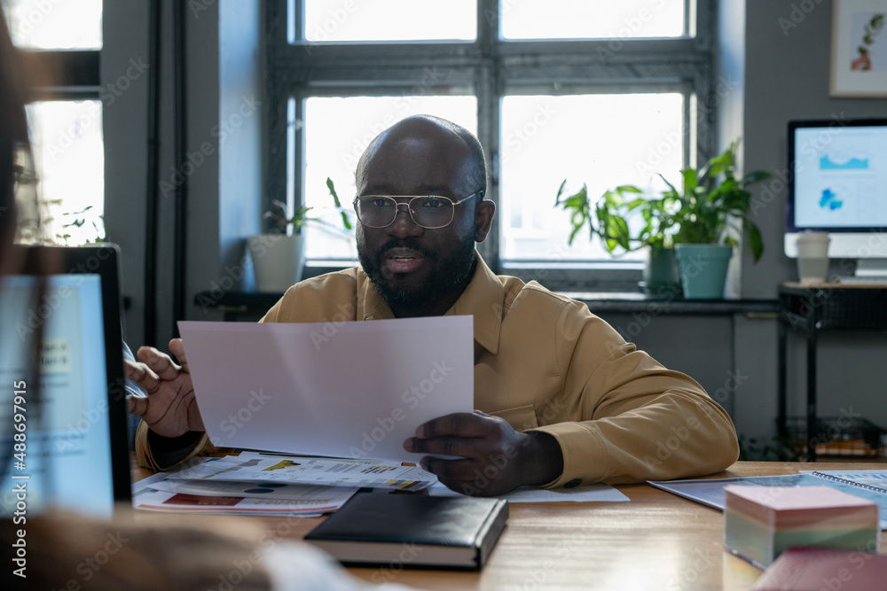 Aufkleber confident african-american economist with paper explaining financial data to colleague while sitting
