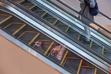 Escalator steps in a shopping mall. A man climbs up the escalator from the first to the second floor.