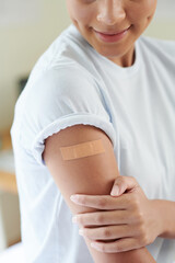 Vaccination of little girl in doctors office, kid with adhesive plaster on her arm after vaccine from covid
