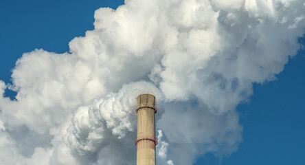 Powerful industrial factory chimney is smoking and polluting the environment with carbon dioxide