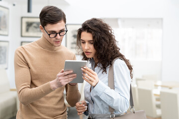 Young confident programmer of high tech company making presentation of online data analysis to colleague or client in large modern office