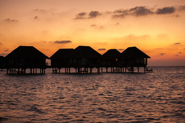 Fototapeta na wymiar Sunset over Water Bungalows in Turquoise Sea at Maldives
