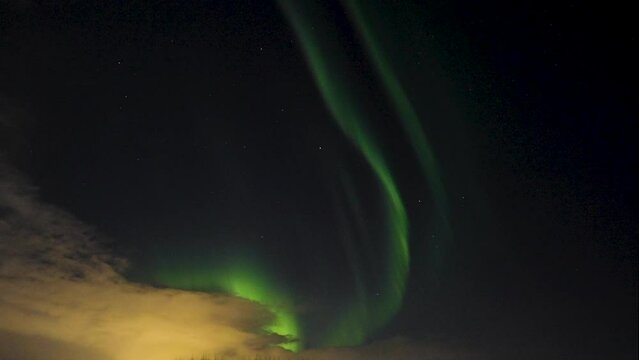 Bottom up shot of green Aurora Borealis on dark sky and yellow colored clouds at night - Iceland,Europe