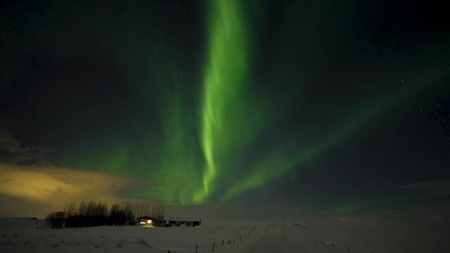 Wide shot of cottage in snowy landscape of Iceland and green Polar Light at dark sky - Expedition of Aurora Borealis in Iceland