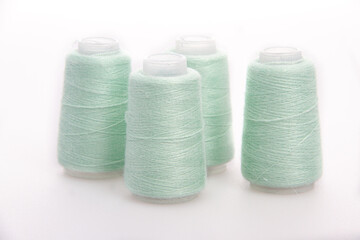 Green spool of thread isolated on white background. Skein of woolen threads. Yarn for knitting. Materials for sewing machine. Coil
