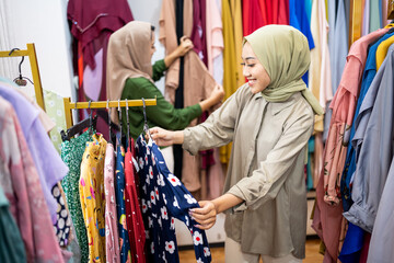 Fototapeta na wymiar muslim female buying new dress at fashion store with her friend