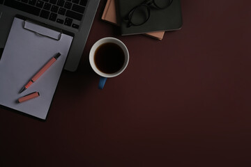 Cup of coffee, notepad and computer laptop on purple background.