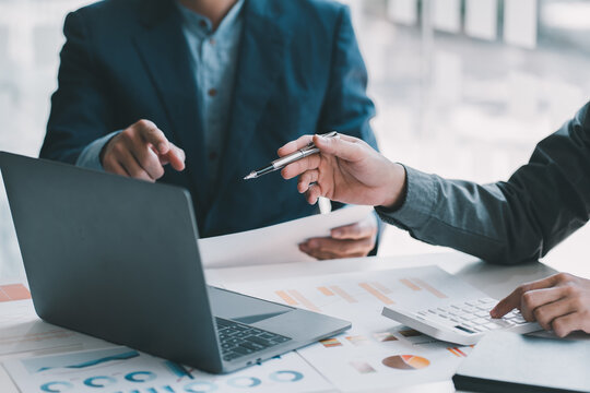Business team two colleagues discussing new plan financial graph data on office table with laptop and digital tablet.
