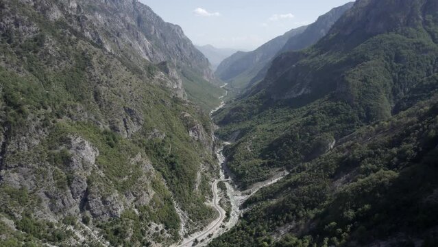 Drone video of frontal descending plane between the hills of the valbone valley and over the Azem Hajdariy road and the river. The beauty of the landscape can be appreciated from a bird's eye view.