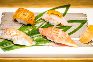 a variety of handmade nigiri sushi served on a porcelain slab