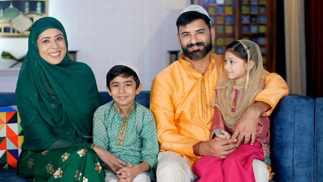 Modern nuclear Muslim family in India - Happy family with two kids and young parents. A happy Muslim family in an ethnic dress sitting together in the living room while posing for the camera - fami...