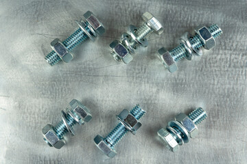 Fasteners for assembling threaded connections. Nuts and bolts. Close-up on the background of a metal blank. Copy space