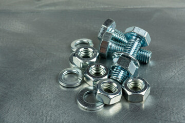 Fasteners for assembling threaded connections. Nuts and bolts. Close-up on the background of a metal blank. Copy space