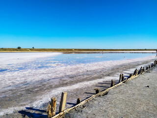 Midday on the salt lake beach under the boundless sky. Calm day view with mirror water at summer. Landscape of the salt desert illuminated by the midday sun.