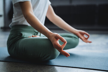 A young girl sits in the lotus position of her hand on her lap, her fingers folded into the rank of...