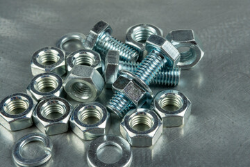 Fasteners for assembling threaded connections. Nuts and bolts. Close-up on the background of a metal blank. Copy space