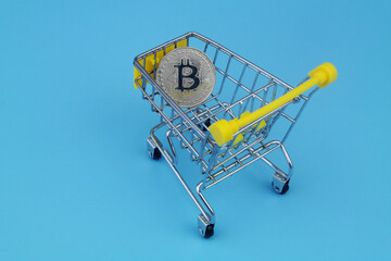 Purchase bitcoins concept. Shopping cart and bitcoin on blue background. 