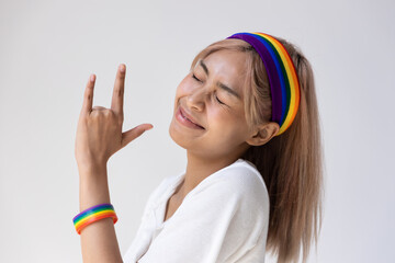 Happy LGBT woman wearing LGBTQ rainbow headband showing love hand sign, concept of gay pride month,...