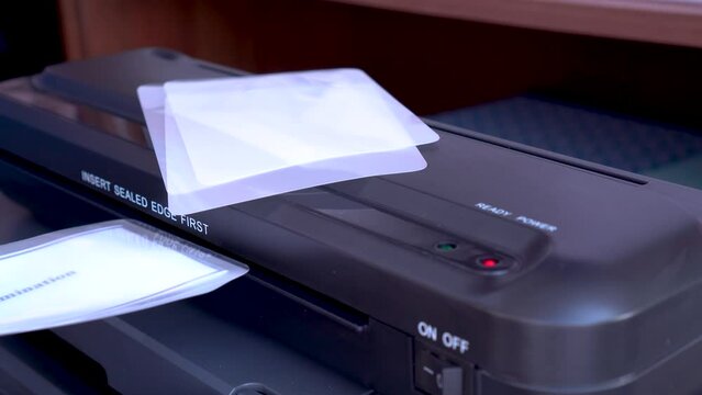The Work Of The Laminator. close-up, selective focus. device for applying a transparent film to documents, photos, which reliably protects them from dust, moisture and other external influences.