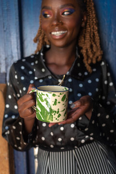 Portrait of young African woman holding a metal mug of tea