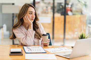 Smiling Asian businesswoman holding a coffee mug and laptop at the office. business concept.