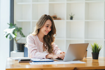 Portrait young attractive beautiful asia female sit on desk smile to camera work at home remotely...