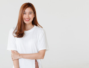 Portrait isolated cutout studio shot of Asian young happy cheerful long brown hair female teenager model in casual shirt standing smiling look at camera holding hand on elbow on white background