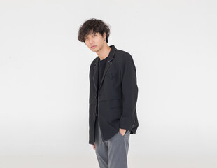 Obraz na płótnie Canvas Portrait isolated cutout studio shot of Asian urban young trendy fashion stylish male model in casual hipster streetwear suit and earrings standing holding hands in pants pockets on white background