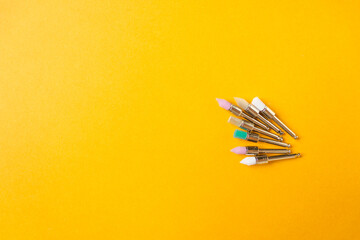 Metal nozzles with multicolored brushes for professional teeth cleaning of dogs and cats. Isolated on yellow background.