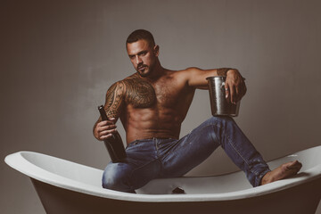 Sexy man on bathtub with champagne. Celebrating gay christmas or birthday. Private sex party.