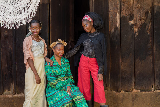 Portrait of three young african women in front of a rural home 