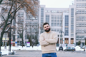 Urban portrait of young elegant business man in winter casual clothes, jacket, hat. Walking in the city street, talking on the phone, making selfie. Working outdoor