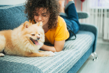 Curly haired woman playing with her dog at home.