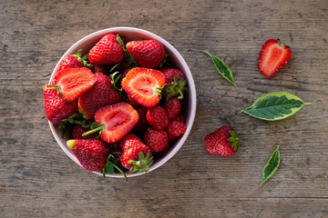 ripe fresh strawberries in a pink plate stand on a wooden table, top view