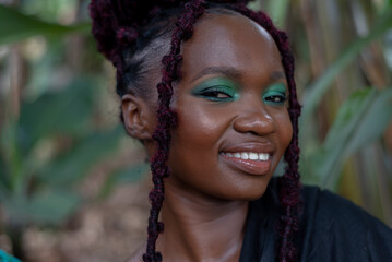 Portrait of a smiling young African woman, in a farm, with long red braids - obrazy, fototapety, plakaty