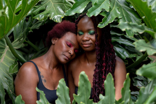 Portrait of two African woman laughing, in leaves, 