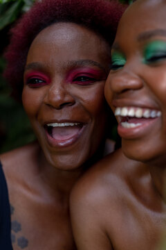 Portrait of two African woman laughing, in leaves, 

