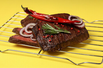Concept of tasty food with beef steaks on yellow background