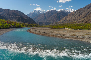 Beautiful Ghizer river, blue river surrounded by Hindu Gush mountains range in blossom season, Gilgit Baltistan, northern Pakistan