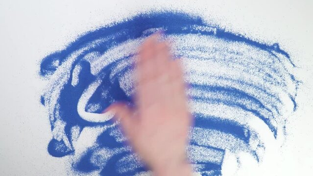 Write 2023 on blue sand year. Painting in the sand. Draw with your hands on the croup. Hand drawing. Erase text by hand. wash
