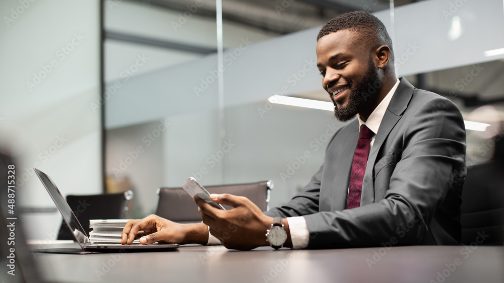 Wall mural Handsome black businessman using modern gadgets in business process, panorama