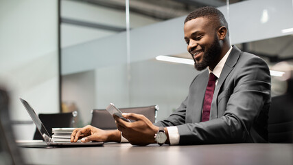 Handsome black businessman using modern gadgets in business process, panorama