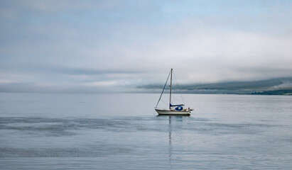 Anchored sailboat in a bay close to the coast of the Isle of Colonsay, Inner Hebrides, Scotland. Early morning