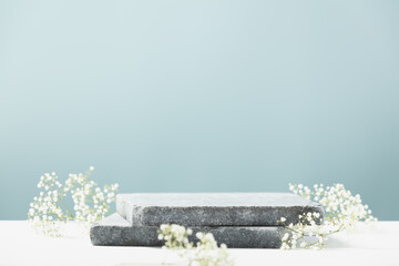Flat granite pedestal and white flowers on blue background.  Showcase for cosmetic products....